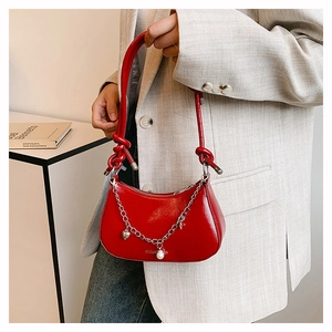 Close-up of red patent leather crescent bag with silver chain and heart pendant