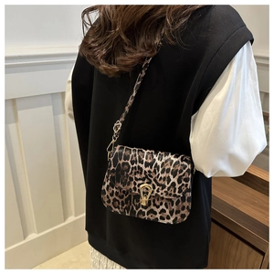 Close-up of leopard print crossbody bag with gold buckle on a model in minimalist attire