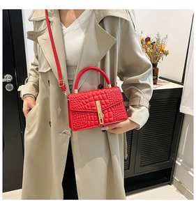 Red crocodile embossed handbag with golden lock shown on a beige trench coat