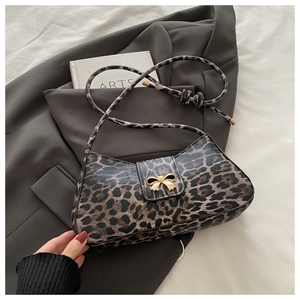 Detail of leopard print handbag with a gold bow buckle on a stylish grey blazer