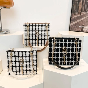 Plaid tweed tote bag with gold S-logo and chain strap on minimalist display stand