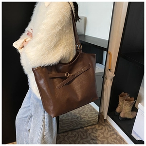 Retro coffee brown faux leather tote bag with decorative straps shown on a model