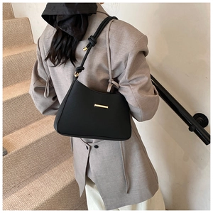 Detail of black underarm bag with gold buckle and unique knotted strap on shoulder