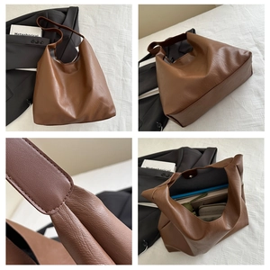 Detail view of brown leather tote bag showing stitching, base, and spacious interior