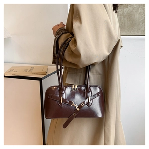 Detail of dark brown vintage handbag with gold buckle shown on a khaki trench coat