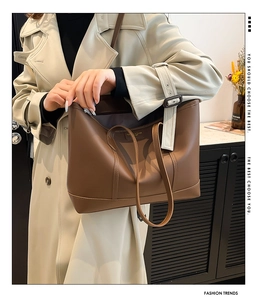 Detailansicht einer großen braunen Leder-Tote-Bag, getragen von einem Model im Trenchcoat