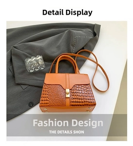 Detail view of brown crocodile-textured leather handbag with golden twist lock and shoulder strap