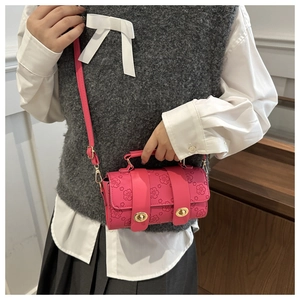 Detailed view of the dark pink floral embossed texture and golden hardware on the cylindrical bag