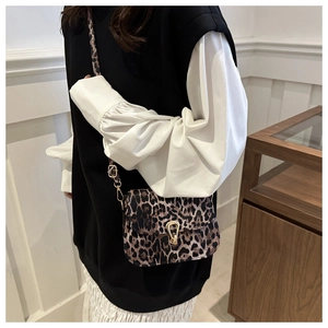 Detailed view of leopard print shoulder bag with gold horseshoe buckle on model