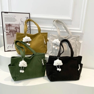 Corduroy tote bags in four colors with cloud charms displayed on a white stand