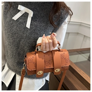 Close-up of brown Boston bag with intricate floral embossing and golden metal hardware