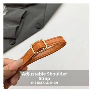 Detail of adjustable caramel brown leather shoulder strap with gold buckle and stitching