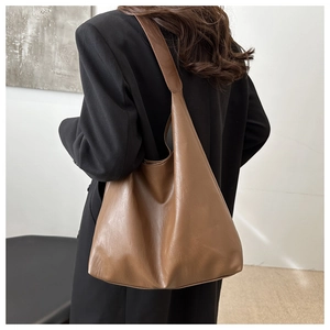 Rear view of model wearing a large brown PU leather tote bag with soft texture