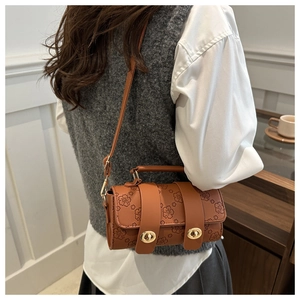 Detailed view of a brown cylinder bag with floral embossing and gold clasp closure