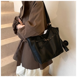 Detailed view of black leather tote bag with textured finish and golden buckle hardware
