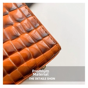 Close-up of caramel brown crocodile texture leather with glossy finish and fine stitching