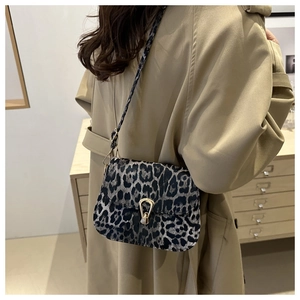 Stylish leopard print shoulder bag with gold horseshoe buckle worn with a beige coat