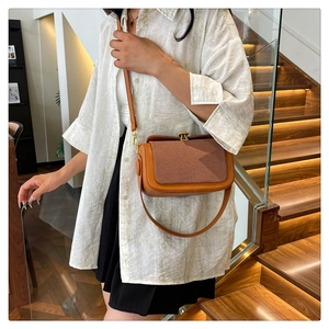 Détail du sac bandoulière en similicuir orange avec texture tissée et boucle dorée