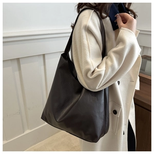 Side view of model wearing the large dark brown matte PU leather tote bag indoors
