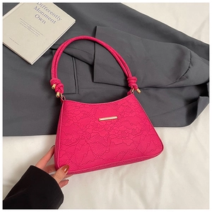 Close-up of rose red underarm bag featuring intricate floral lace texture and gold hardware