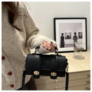 Close-up of black Boston bag with embossed cherry blossoms and gold twist-lock hardware