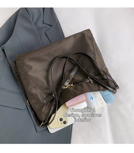 Detail of a large brown nylon tote bag with leather handles on a grey blazer background