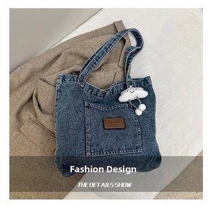 Detail van blauwe denim draagtas met leren logo-label en pluche wolkenvormige hanger