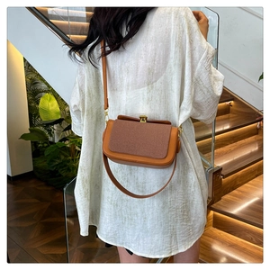 Détail du sac bandoulière en cuir orange et marron avec texture et fermoir doré