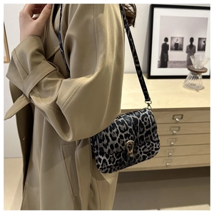 Leopard print saddle bag with gold U-buckle worn by model in a beige trench coat