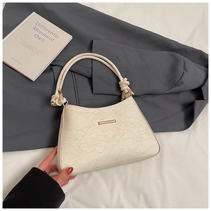 Detail of white lace embossed leather underarm bag with gold metal trim and knotted handle