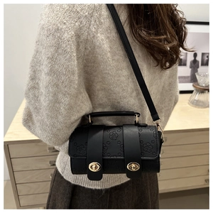 Detail of black Boston bag with 3D floral texture and gold twist lock closure