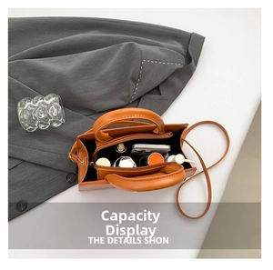 Interior view showing the large storage capacity for cosmetics and phone in orange leather bag