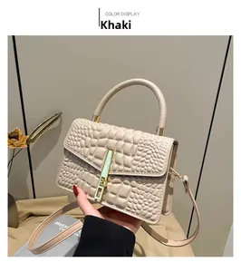 Detail of khaki crocodile pattern handbag with gold clasp and curved top handle