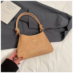 Close-up of elegant lace-embossed shoulder bag with golden hardware and knotted strap