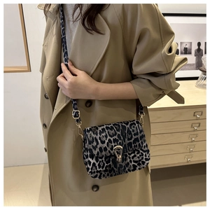 Detail of leopard print crossbody bag with gold horseshoe buckle on beige trench coat