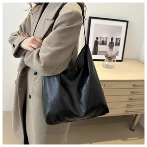 Classic black PU leather tote bag worn by model in a minimalist modern interior