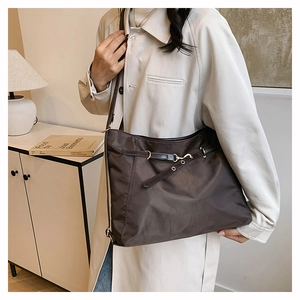 Detail of coffee nylon tote bag with leather strap and metal hook on model in home setting