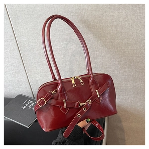 Detail of burgundy leather shoulder bag with gold hardware and fashion embossing
