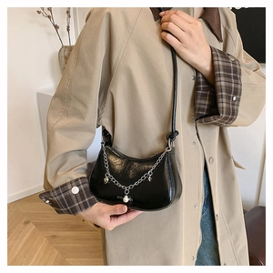 Detail of black leather crescent underarm bag with silver chain and pearl heart pendant