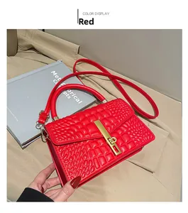 Close-up of red crocodile embossed leather handbag with golden buckle on beige fabric