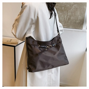 Detail of a dark coffee nylon tote bag with decorative buckle and metal eyelets