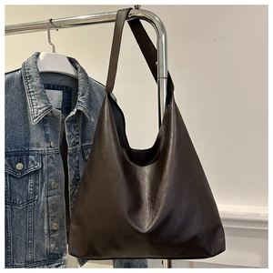 Detail of soft dark brown leather hobo bag hanging over a denim jacket for commute