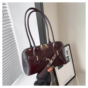 Close-up of a vintage dark burgundy faux leather handbag with gold zipper and belt detail
