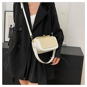 Détail d'un sac à bandoulière cylindrique chic avec texture tissée porté par un mannequin