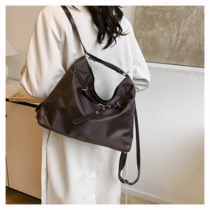 Detail of soft dark brown nylon tote bag with golden metal buckles and adjustable strap