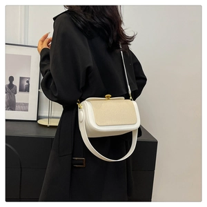 Détail d'un sac bandoulière crème avec boucle dorée sur un mannequin en manteau noir