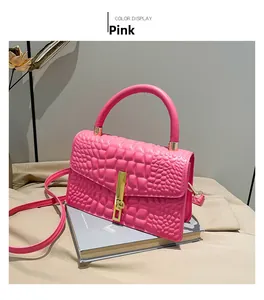 Detailed view of pink crocodile embossed handbag with premium golden metal lock and clasp