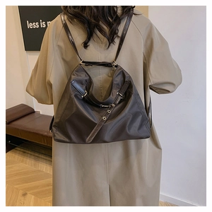 Detail view of dark brown nylon tote bag showing metallic buckles and water-resistant fabric