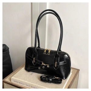 Detail of black glossy bowling bag with gold hardware and removable shoulder strap