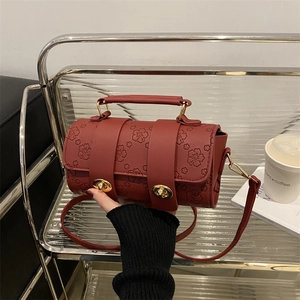 Vintage wine red Boston bag with floral embossing and gold metal locks in hand